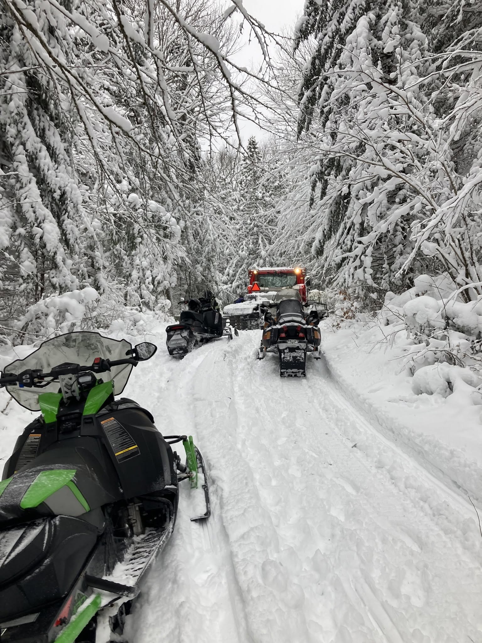 Groomer and snowmobile during trail maintenance