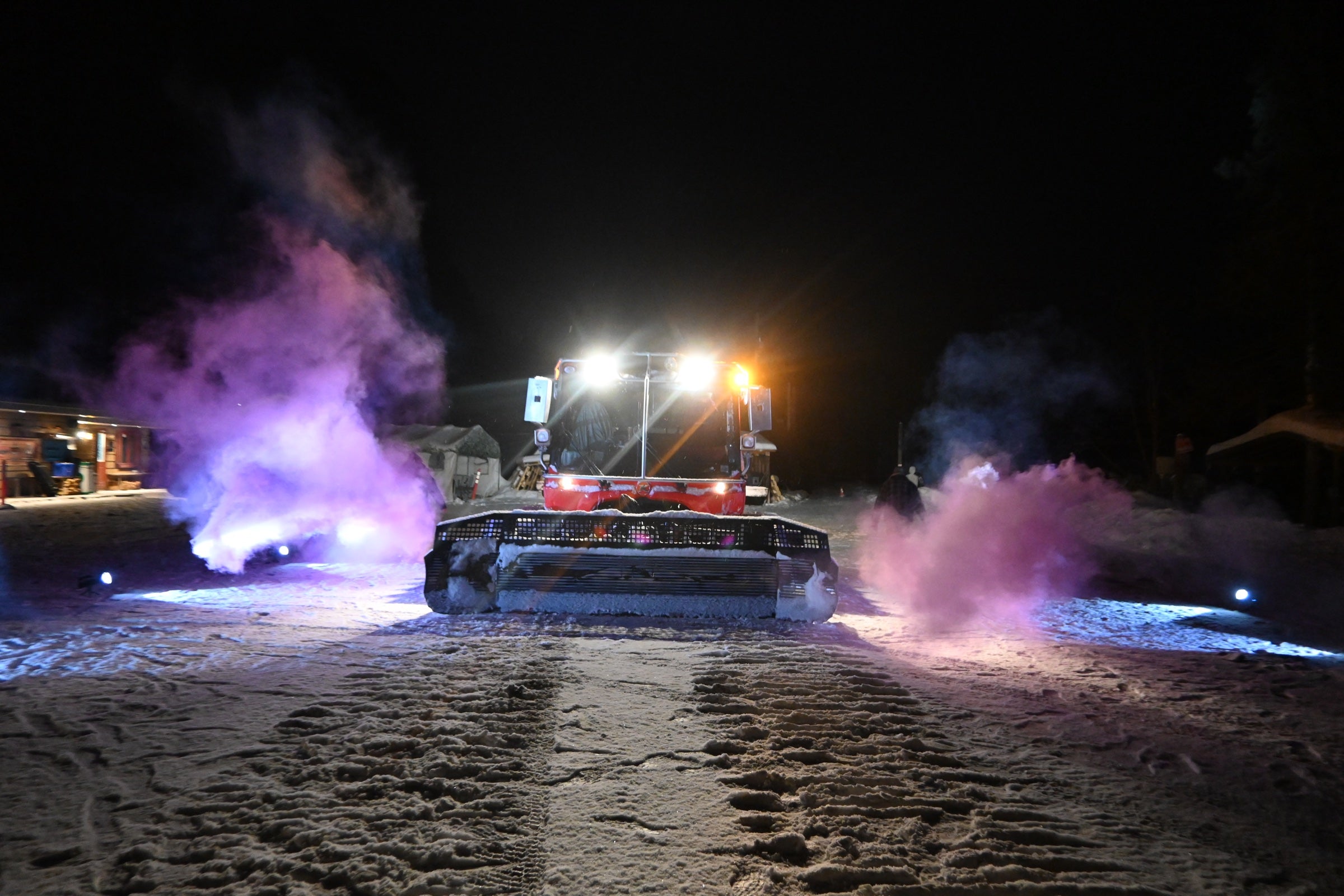 Red BR trail groomer surrounded by steam in the snow