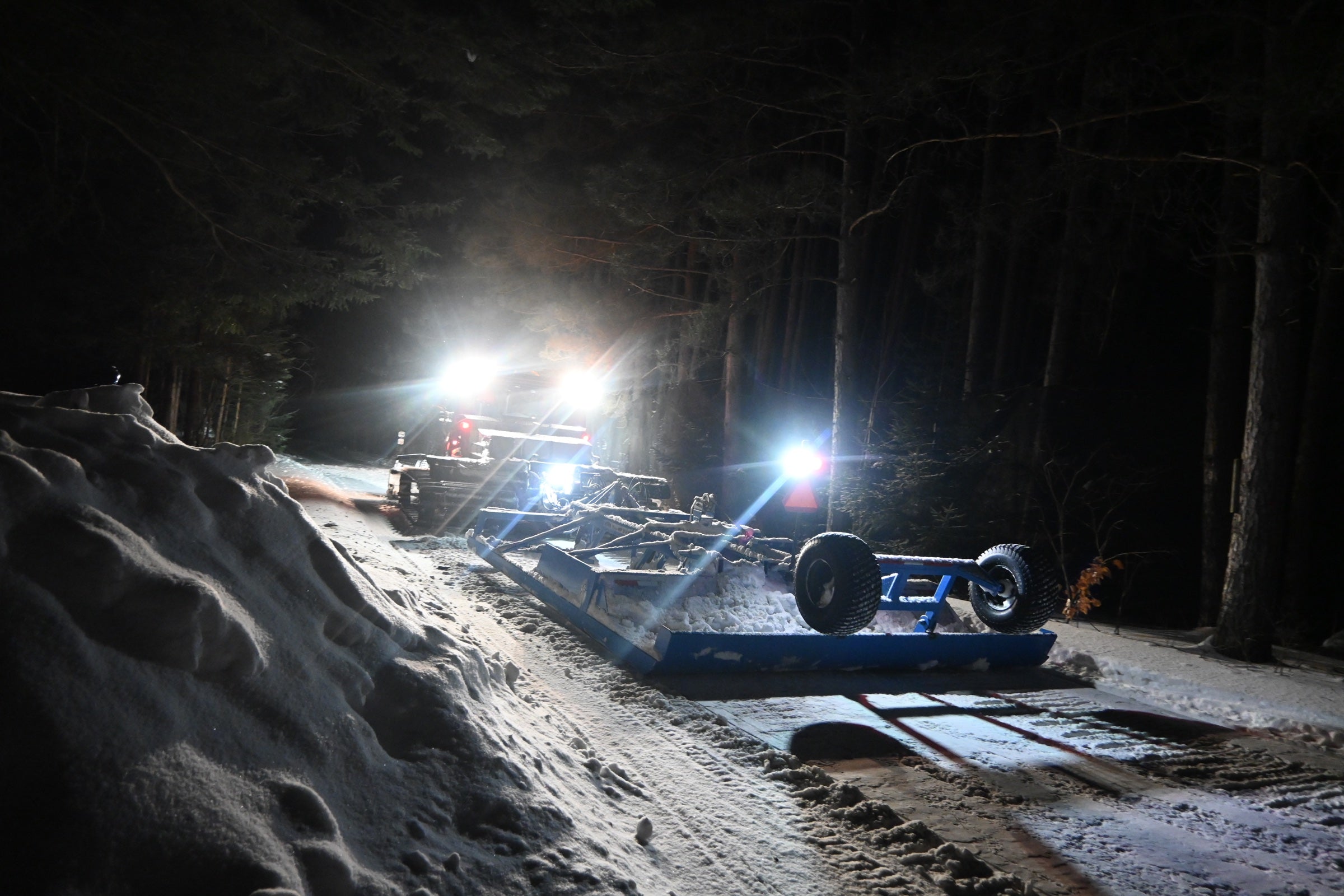 Trail grooming equipment on a snowy trail at night
